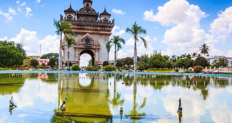 Un monument avec des palmiers et des jardins au premier plan.