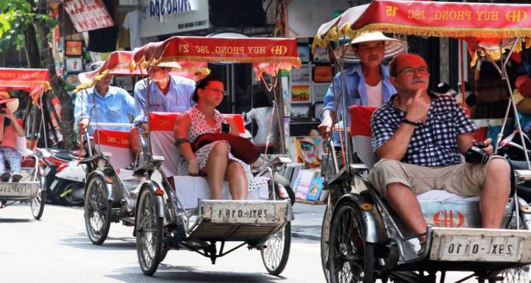 Des gens qui se déplacent en pousse-pousse traditionnels dans une rue de la ville.