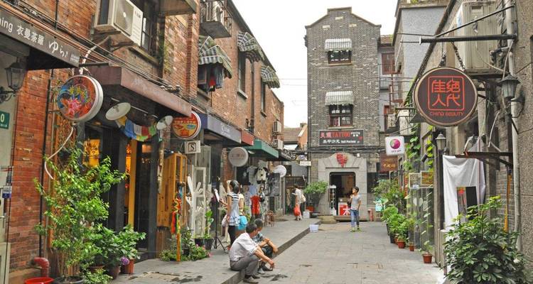 Smalle stadsstraat met verschillende winkels en wandelende mensen.