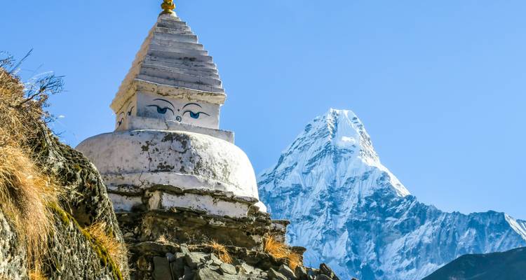 Stupa on a rocky outcrop with a snowy peak behind.