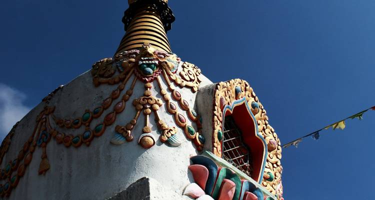 Kleurrijke stupa met ingewikkelde decoraties tegen een blauwe lucht.