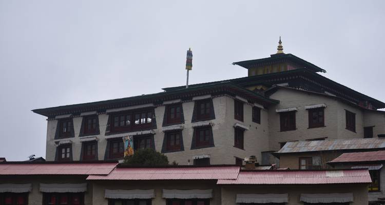 Groot gebouw met traditionele architectuur en bewolkte achtergrond.