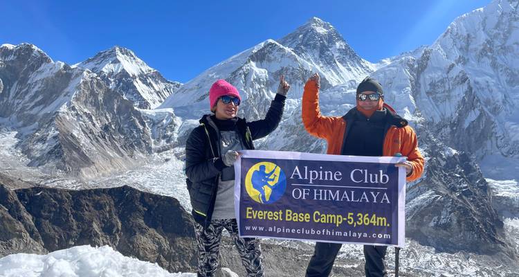 Twee mensen met Mount Everest op de achtergrond bij het basiskamp.