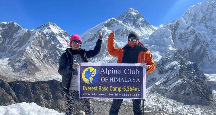 Twee mensen die een Everest Base Camp bord vasthouden.
