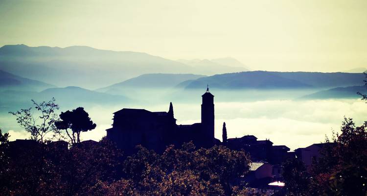 Silhouettes d'un village avec des montagnes brumeuses en arrière-plan.