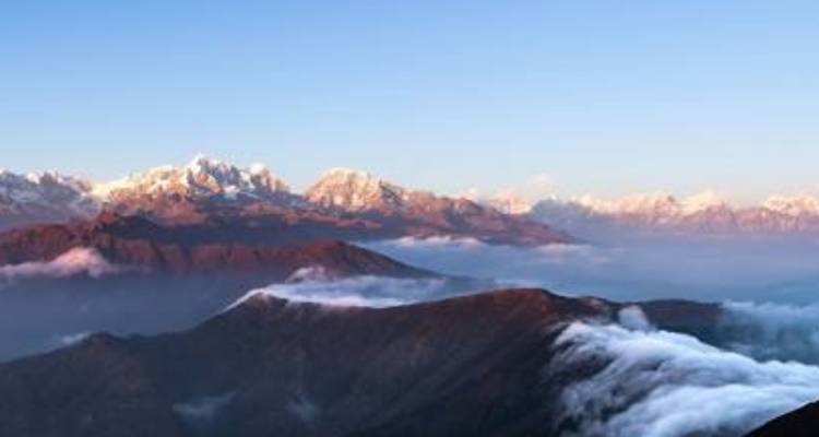 Gebirgszug im Nebel während des Sonnenaufgangs.