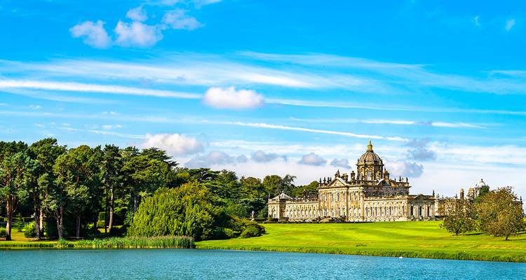 Historical manor on a lake with lush green surroundings.