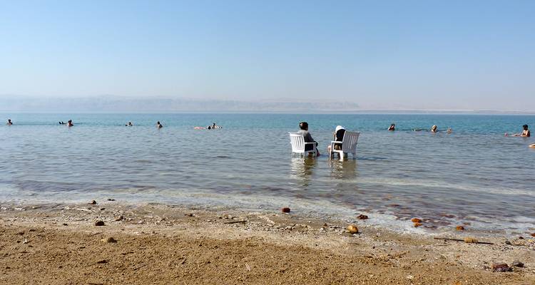 Menschen, die im Toten Meer sitzen und treiben.