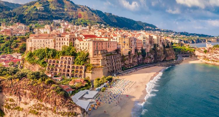 Küstenstadt mit Sandstrand und Klippen, die sich ins Meer erstrecken.