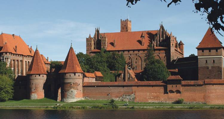 Mittelalterliche Backsteinburg mit einem Fluss im Vordergrund.