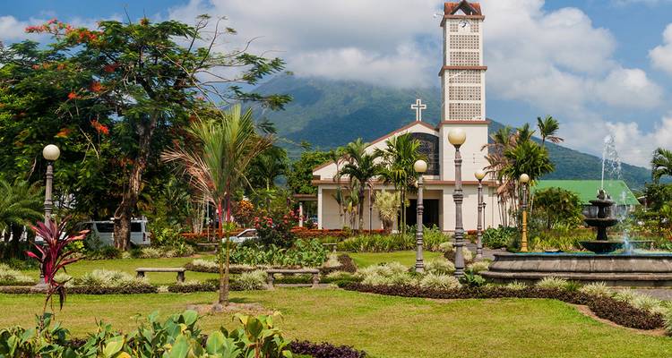 Église avec un arrière-plan pittoresque de montagnes et un jardin bien entretenu.