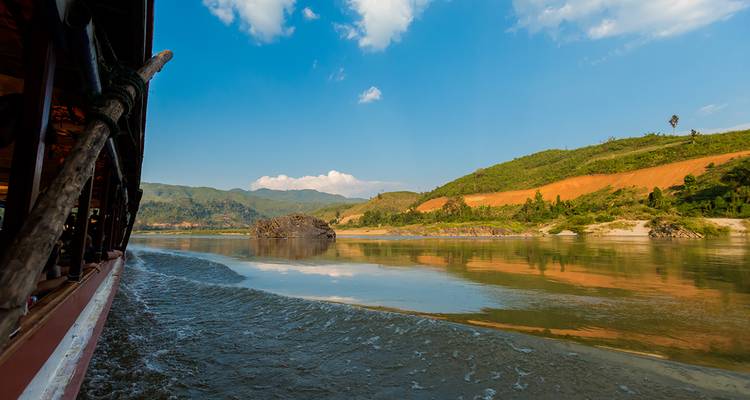 Blick von einem Boot auf einem Fluss mit Hügeln und Wolken