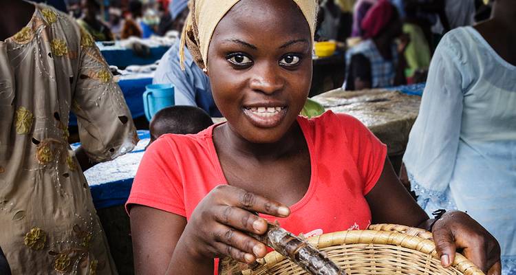 Frau hält einen Korb mit Fisch auf einem Markt.