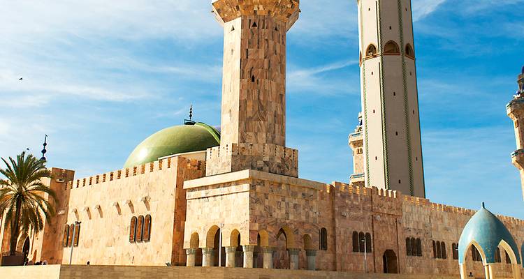 Moschee mit Kuppeln und Minaretten unter blauem Himmel.