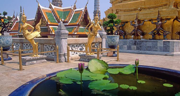 Ornate golden statues and a lotus pond within a temple complex.
