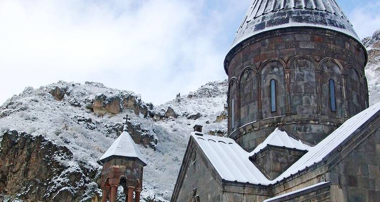 Schneebedecktes Kloster mit bergiger Kulisse.