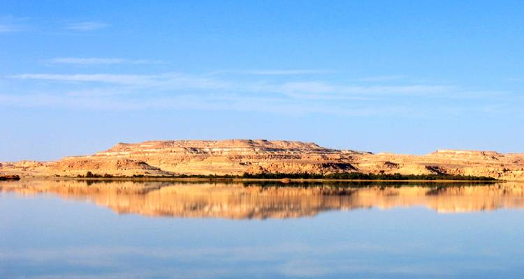 Woestijnbergen weerspiegeld in een stil wateroppervlak.