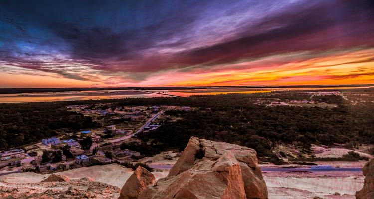 Zonsondergang boven een woestijnstad met kleurrijke lucht.