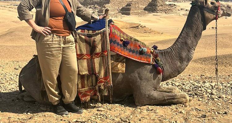 Persoon met camera staand bij kameel.