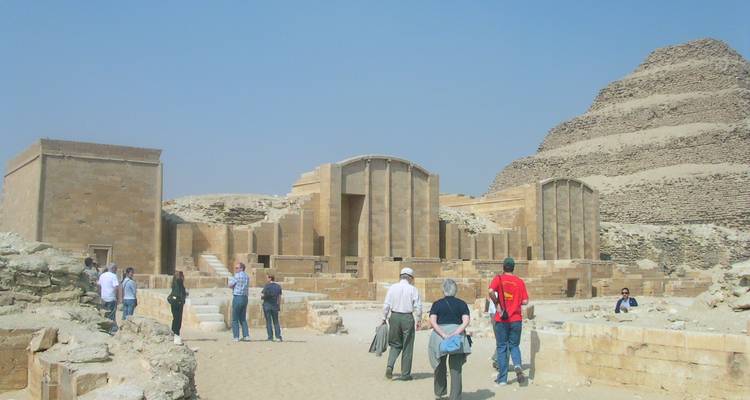 Toeristen die een oude Egyptische site met piramidevormige structuur verkennen.