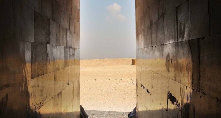 Uitzicht door een opening van een oude structuur naar een woestijnlandschap.