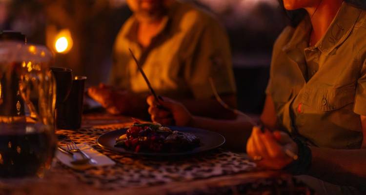 Menschen, die im Freien bei Laternenschein speisen.