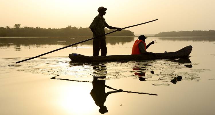 Deux personnes dans un canoë sur un plan d'eau calme au coucher du soleil.