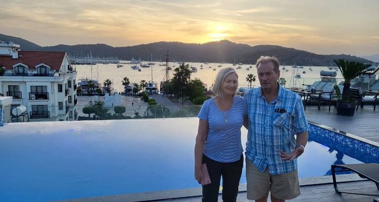 Couple standing by an infinity pool during sunset.