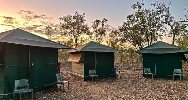 Installation de camp sous tentes avec un coucher de soleil pittoresque en arrière-plan.