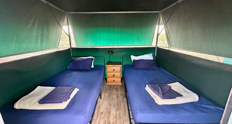 Deux lits à l'intérieur d'une tente, représentant un hébergement de camp simple.