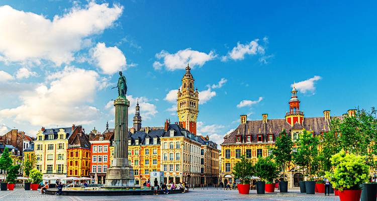 Farbenfroher Stadtplatz mit historischen Gebäuden und einer Statue.