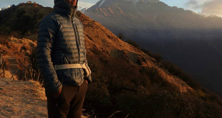 Persona con chaqueta de invierno de pie con un telón de fondo montañoso.