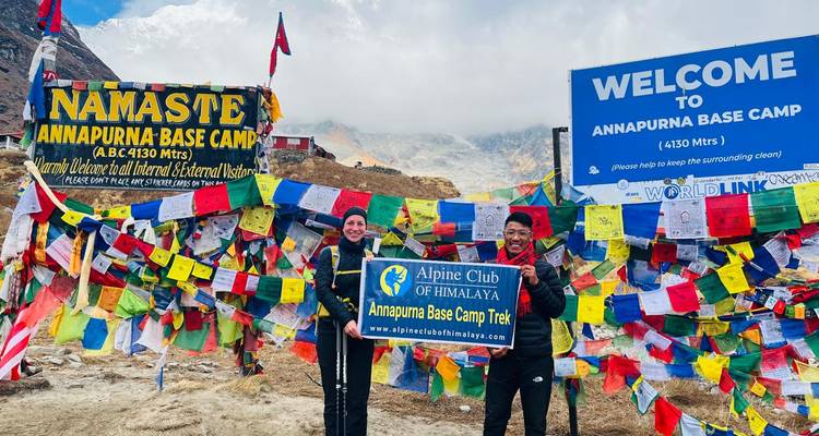 Menschen, die am Annapurna Base Camp mit Flaggen und Schildern stehen.