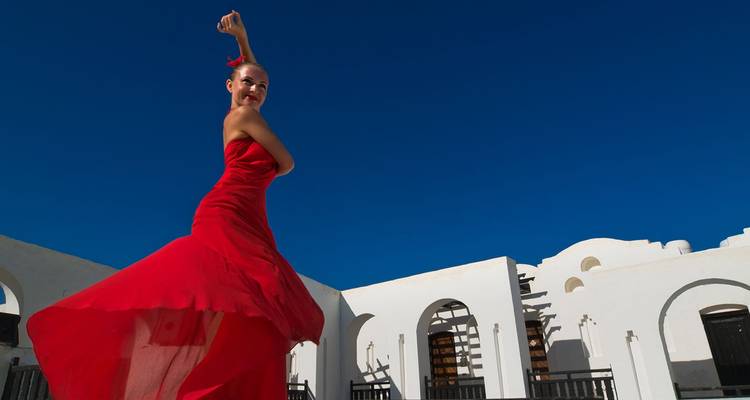 Danseur de flamenco dans une robe rouge fluide se produisant sous un ciel bleu éclatant dans une cour traditionnelle