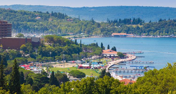 Coastal view of Portoroz with green hills and a marina.