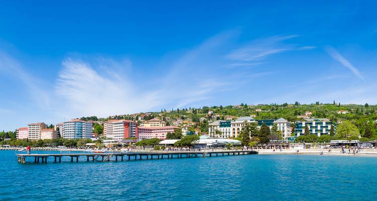 Une ville côtière avec un océan bleu, des bâtiments et une jetée sous un ciel dégagé.