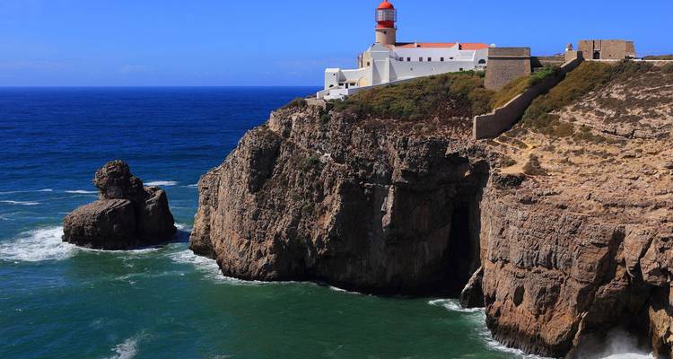 El faro de Cabo San Vicente encaramado en los espectaculares acantilados del mar con las profundas olas azules del Atlántico chocando abajo