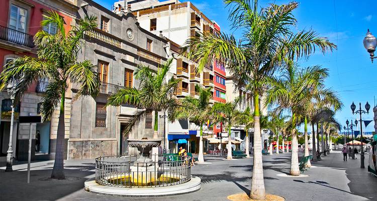 Plaza bordeada de palmeras con fuentes y fachadas coloridas en Santa Cruz de Tenerife.