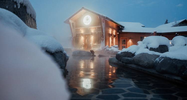 Une source chaude couverte de neige avec une personne près de l'entrée.