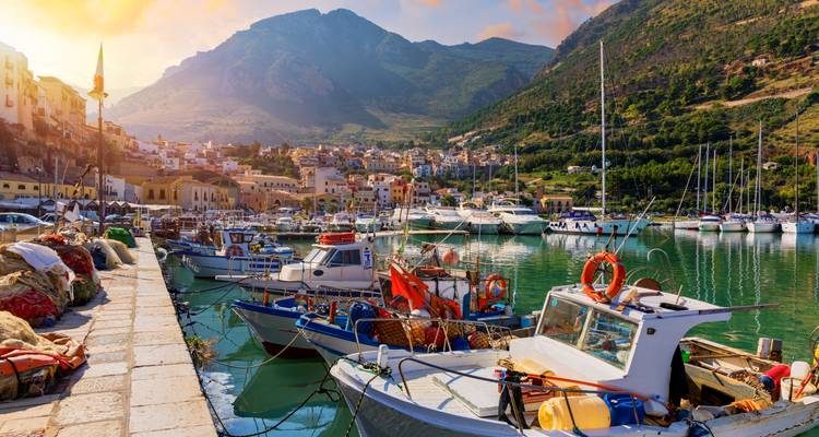 Bateaux de pêche amarrés dans une marina avec un paysage de collines en arrière-plan.