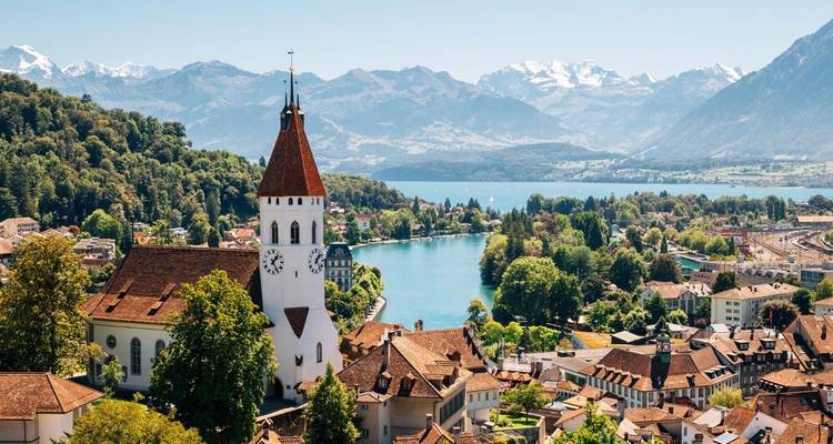 Charmante ville lacustre suisse avec clocher, toitures et Alpes enneigées au-delà.