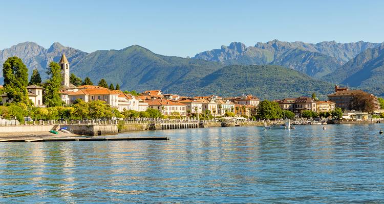 Pueblo ribereño con montañas al fondo.