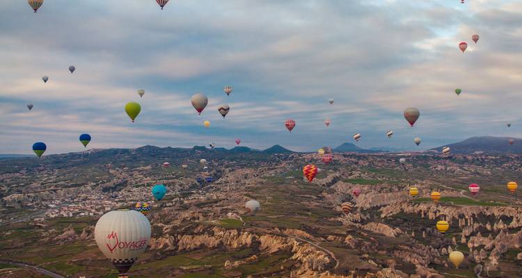 Hunderte bunte Heißluftballons treiben bei Sonnenaufgang über Cappadociens surreale Täler.