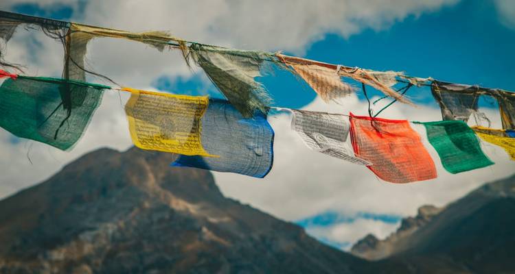Gebedsvlaggen tegen een bergachtige achtergrond onder een bewolkte hemel.