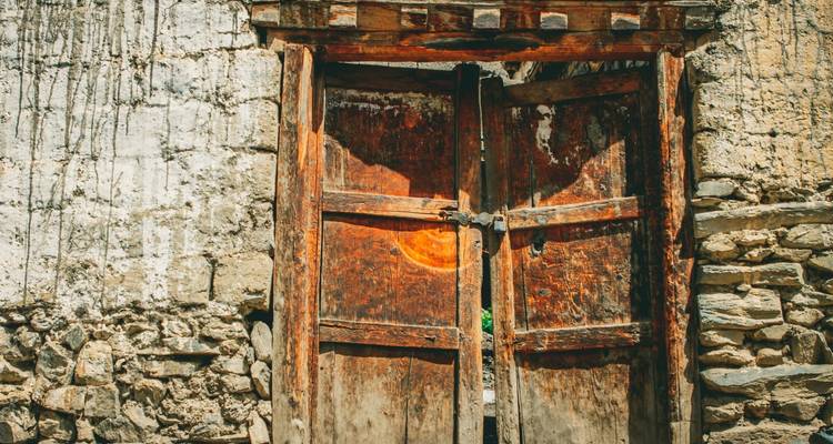 Oude houten deur ingebed in een stenen muur in het zonlicht.