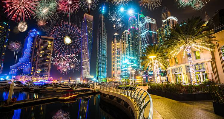 Feux d'artifice la nuit au-dessus d'un front de mer avec de grands bâtiments modernes.