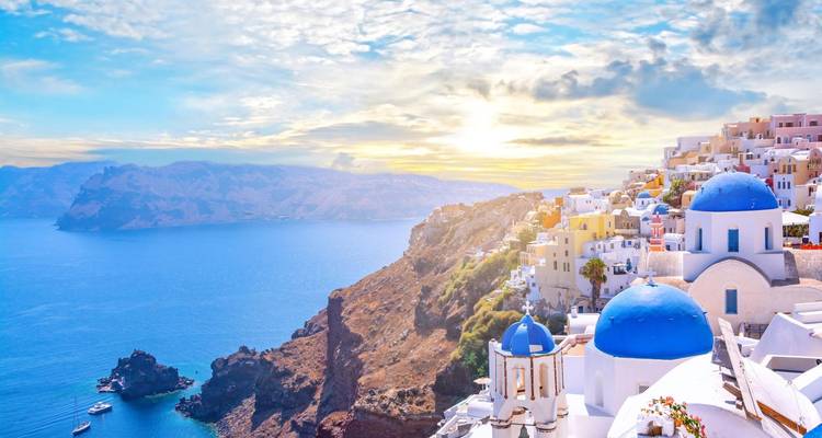 Des bâtiments blancs avec des dômes bleus sur une falaise.