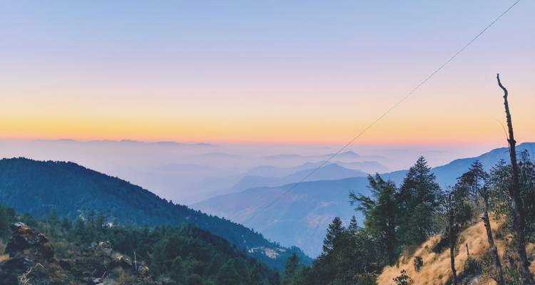 Sonnenuntergangsblick auf Bergketten mit grünen Wäldern.