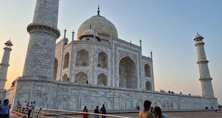 Side view of the marble Taj Mahal with visitors on the terrace during golden hour.