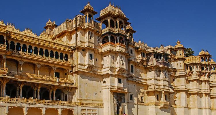 Ornate facade of Udaipur’s City Palace gleams under a clear blue sky.